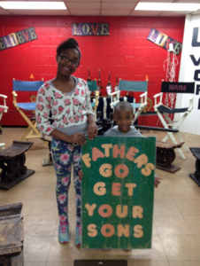 Two young people holding a fathers go get your sons sign