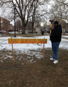 Kevin Barfield putting up a six foot keep love present sign in the community of camden, nj